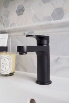 a black faucet sitting on top of a bathroom sink next to a soap dispenser