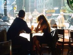 a man and woman sitting at a table in front of a window with the sun shining on them