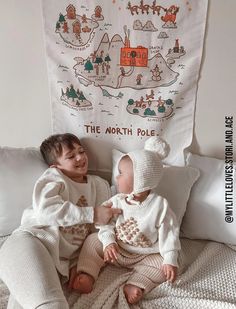 two children sitting on a bed next to a wall with a banner above them that says the north pole