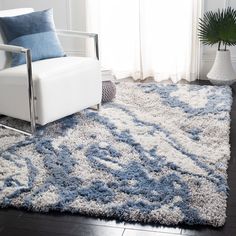 a white chair sitting on top of a rug in a living room next to a window