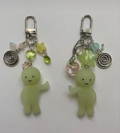 two keychains with charms attached to them on a white surface, one is green and the other is yellow