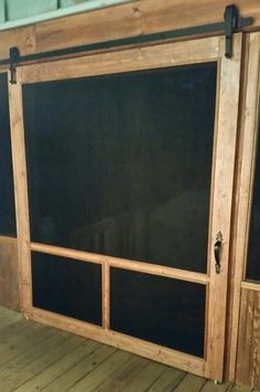 an open sliding door on the side of a wooden building with black glass panels and wood flooring