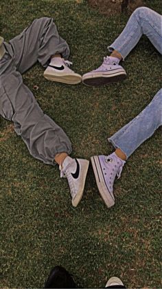 two people laying in the grass with their feet on each other