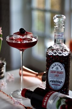 a bottle of cherry brandy next to a wine glass with a red liquid in it