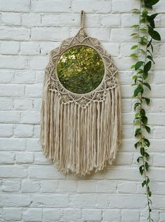 a white brick wall with a round mirror hanging on it's side next to a green plant