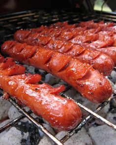 hot dogs and sausages cooking on an outdoor grill