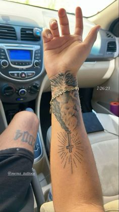 a person with a tattoo on their arm and wrist holding up his hand in the car