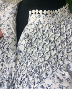 there is a white and blue flowered dress with buttons on the front, but it has ruffles at the bottom