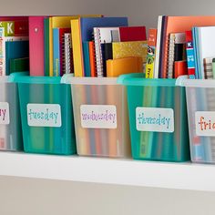 plastic bins with stickers on them sitting on a shelf in front of books