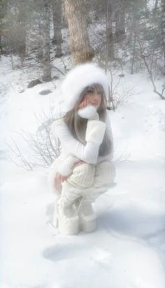 a woman in white is sitting in the snow with her hands on her face and looking at the camera