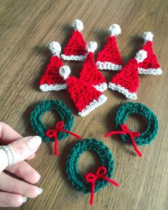 crocheted santa hats and wreaths on a wooden table with yarn tied around them