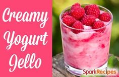 a glass filled with ice cream and raspberries on top of a wooden table