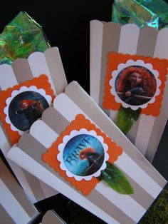 some paper bags with pictures on them sitting next to each other in front of an orange and white striped box