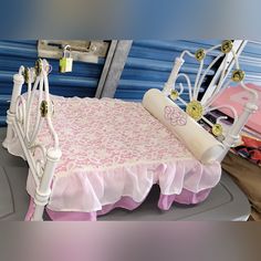 a bed with pink and white bedspread next to stacks of blue mattresses