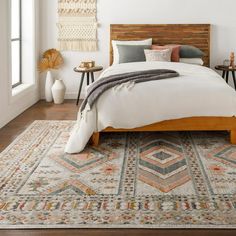 a large bed sitting on top of a wooden floor next to a white wall in a bedroom