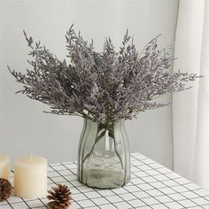 a vase filled with purple flowers sitting on top of a table next to two candles