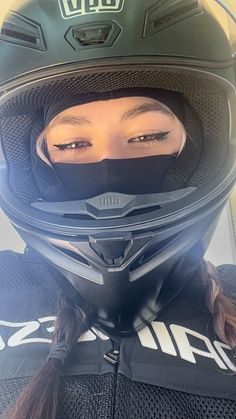 a woman wearing a motorcycle helmet with her eyes wide open