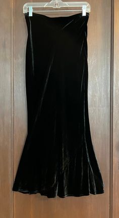 This lovely black 'velvet' full-length skirt from CITRON Santa Monica, circa 1990s, definitely has that Art Deco look and feel to it. It has a gusseted detail at the bottom to give it that bias cut swirl. The hips on the skirt are fuller than that of the model (34-28-34). The waistband has no stretch left to it, but perhaps if you are handy with a needle and thread you can add a piece of elastic. It is made of 82% Rayon and 12% Silk - 100% earth friendly! Closure: Pull On Occasion: Dinner, Dancing, Wedding, Theater, Cocktail Party Size: XS Accents: Gusset at Hemline Size Type: Regular or Petite Skirt Style: Tube/Mermaid Rise: High (Greater than 10.5 in) Waist Size: 28 in Length: 38.5 in Season: All Seasons Garment Care: Dry Clean Only Color: Black Material: 82% Rayon and 12% Silk Front Typ Whimsigoth Dresses, Velvet Skirt Outfit Winter, 2000s Goth Fashion, Long Black Velvet Skirt, Black Mermaid Skirt, Velvet Black Skirt, Whimsigoth Skirt, Velvet Skirt Outfit, Mermaid Maxi Skirt