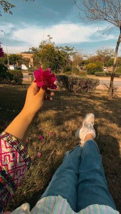 a person laying on the ground with their feet up holding a flower in front of them