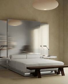 a white bed sitting in a bedroom next to a wall mounted mirror on the wall