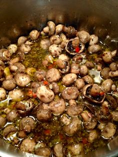 mushrooms are being cooked in a pot with broth and seasonings on the side