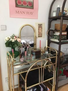 a gold vanity with lots of makeup and other items on the shelf next to it