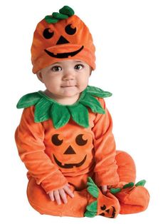 a baby in a pumpkin costume sitting on the ground