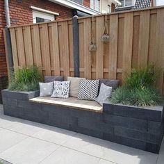 a wooden bench sitting on top of a cement slab next to a green lawn and fence