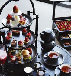 an assortment of desserts and drinks on a table in front of two trays filled with pastries