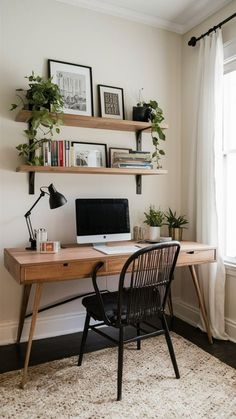 a desk with a computer, books and plants on it in front of a window