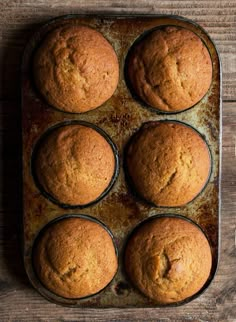 six muffins in a baking pan on a wooden table