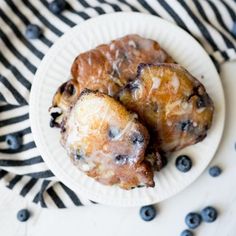 two blueberry pastries on a paper plate with black and white striped table cloth