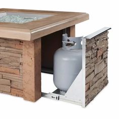 an outdoor table with a propane tank in the center and stone walls around it