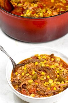 a white bowl filled with chili and corn next to a red casserole dish