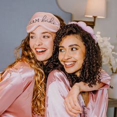 two women dressed in pink posing for the camera with their heads wrapped around each other