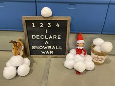 an elf is sitting on top of snowballs next to a sign