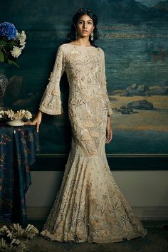 Sand beige bell sleeve fishtail hem gown, highlighted with 3D jungle motif and floral embroidery.
Component: 1
Pattern: Embroidery
Type Of Work: Floral,Jungle Motifs
Neckline: Round Neck
Sleeve Type: Bell Sleeves
Fabric: Soft Net
Color: Beige
Other Details: 
Palm tree, floral and birds embroidered gown
Occasion: Reception,Destination Wedding - Aza Fashions Elegant Bell Sleeve Wedding Dress, Elegant Bell Sleeve Embroidered Dresses, Elegant Embroidered Bell Sleeve Dress, Wedding Embellished Fishtail Gown, Embellished Fishtail Wedding Gown, Embellished Fishtail Gown For Wedding, Sahil Kochhar, Net Embroidery, Zardozi Embroidery