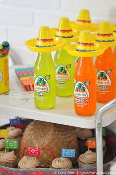 an assortment of orange juices and cupcakes on a table in front of a white brick wall