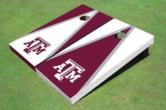 two maroon and white triangle shaped cornhole game pieces on green grass with the letters f & m painted on them