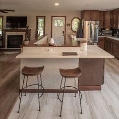 a kitchen with two stools next to an island in the middle of the room