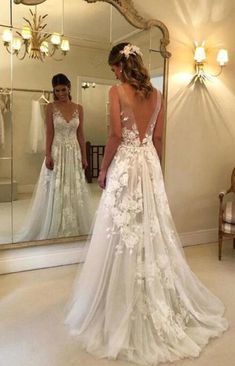 a woman in a wedding dress looking at herself in the mirror with her back to the camera