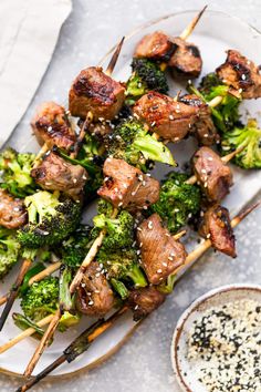 meat and broccoli skewers on a plate with dipping sauce