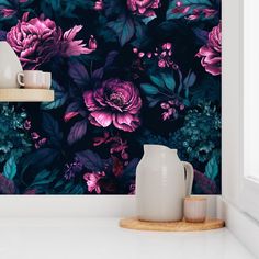 a vase sitting on top of a counter next to a wall covered in purple flowers