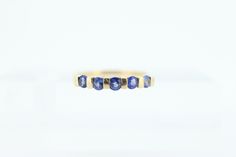 a yellow gold ring with blue sapphires on it's sides, against a white background