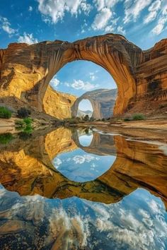 an arch shaped rock formation with water in the foreground and clouds in the background