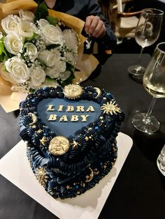 a heart shaped cake sitting on top of a table next to wine glasses and flowers