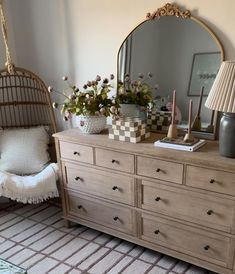 a bedroom with a dresser, mirror and lamp