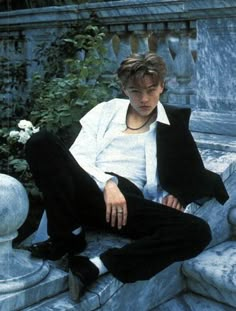 a young man sitting on top of a stone bench