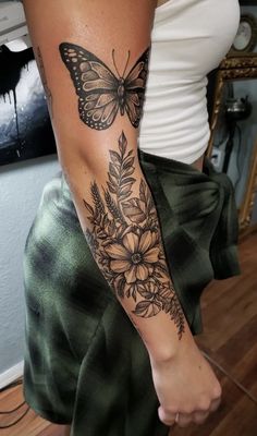 a woman's arm with a butterfly and flowers tattoo on the left side of her arm