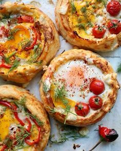 four small pizzas with different toppings on them sitting on a piece of paper